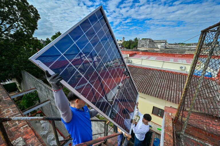 Une équipe de techniciens de systèmes photovoltaïques hisse des panneaux sur le toit d'une cantine pour personnes âgées géré par l’Eglise catholique, dans le quartier de Guanabacoa à La Havane, le 4 février 2026 © ADALBERTO ROQUE