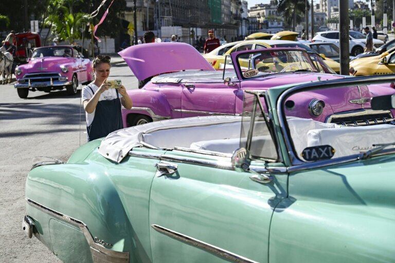 Une touriste prend en photo une voiture américaine dans une rue de La Havane, le 11 février 2026 à Cuba © YAMIL LAGE