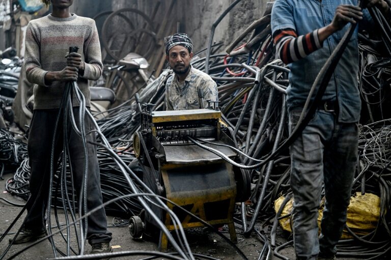 Des hommes récupérant de l'aluminium de fils plastiques dans un centre informel de recyclage de Seelampur, à New Delhi en Inde, le 28 janvier 2026 © Arun SANKAR