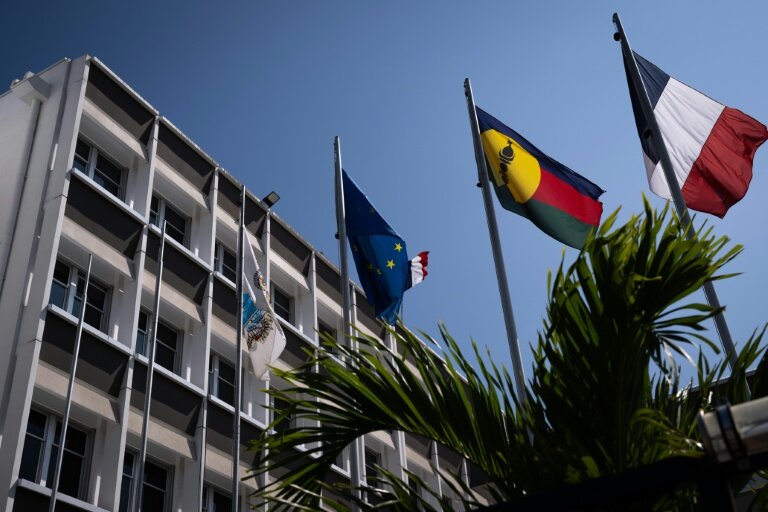 Un drapeau kanak (2e d), le drapeau français (d) et le drapeau européen (2eg) devant l'hôtel de ville de Nouméa, en Nouvelle-Calédonie, le 23 septembre 2024 © SEBASTIEN BOZON