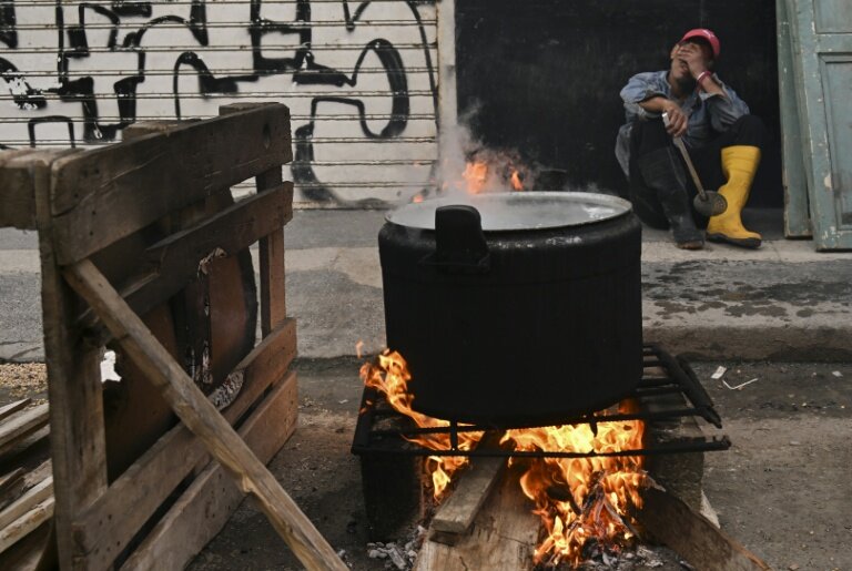 Un homme devant une marmite cuisant au feu de bois dans une rue de La Havane, le 23 février 2026 © YAMIL LAGE