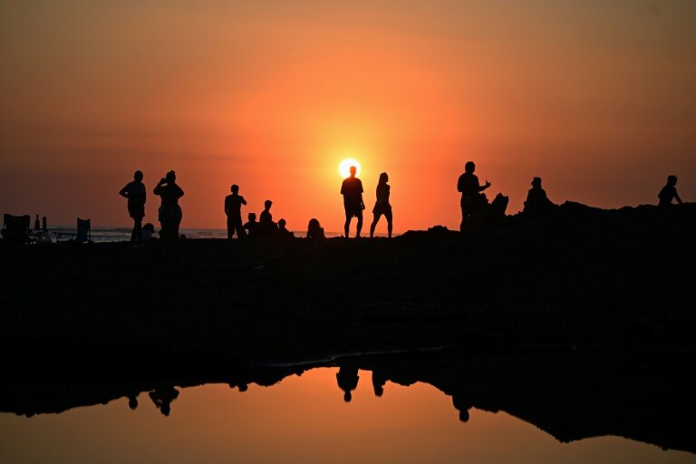 Des touristes profitent du soucher de soleil sur la plage d'El Tunco à La Libertad, au Salvador, le 13 février 2026 © Marvin RECINOS