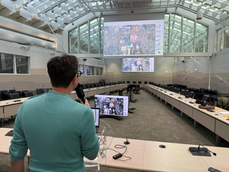 Le journaliste de l'AFP Frédéric Bourigault (à gauche) interroge l'astronaute de l'ESA Sophie Adenot (sur les écrans) qui se trouve à bord de la Station spatiale internationale (ISS), au siège de l'Agence spatiale européenne (ESA) à Paris, le 26 février 2026 © Jacques-Alexandre BRUN