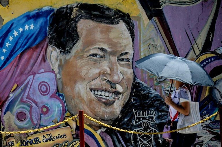 Une femme se protégeant du soleil avec un parapluie arrive au mausolée de l'ancien président vénézuélien Hugo Chavez à Caracas, le 5 mars 2026 © Juan BARRETO