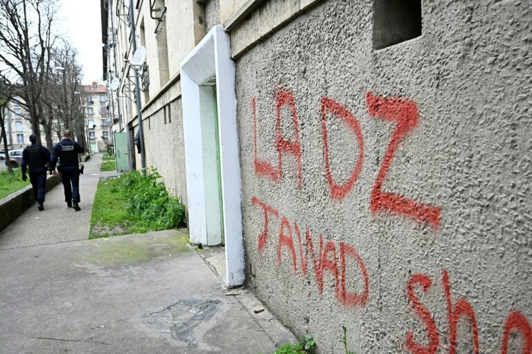 Des policiers patrouillent à proximité d'un mur avec un tag DZ désignant la DZ mafia à Avignon le 13 mars 2025 © GABRIEL BOUYS