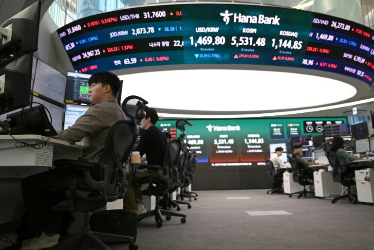 Des cambistes surveillent les taux de change tandis qu'un écran électronique affiche les indices boursiers de référence dans une salle des marchés des changes de la Hana Bank à Séoul, le 10 mars 2026 en Corée du Sud © Jung Yeon-je