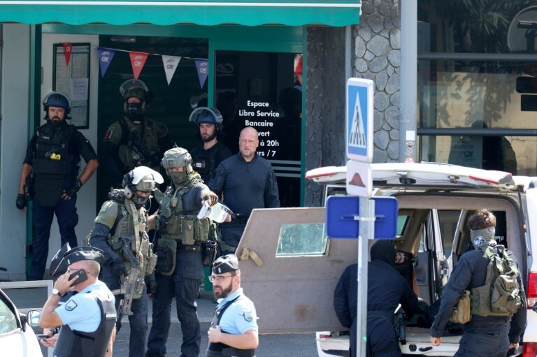 Des gendarmes et des membres de l'unité du Groupe d'intervention de la gendarmerie nationale (GIGN)  devant une agence bancaire où un homme est soupçonné d'avoir  mortellement frappé à l'arme blanche un agent d'entretien, le 28 octobre 2023 à La Possession, sur l'île de La Réunion © Richard BOUHET
