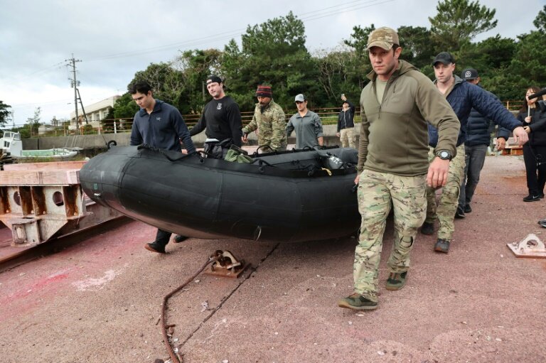 Des personnels militaires américains transportent un canot pour participer aux recherches en mer de l'épave d'un Osprey, sur l'île de Yakushima au Japon le 1er décembre 2023 © STR
