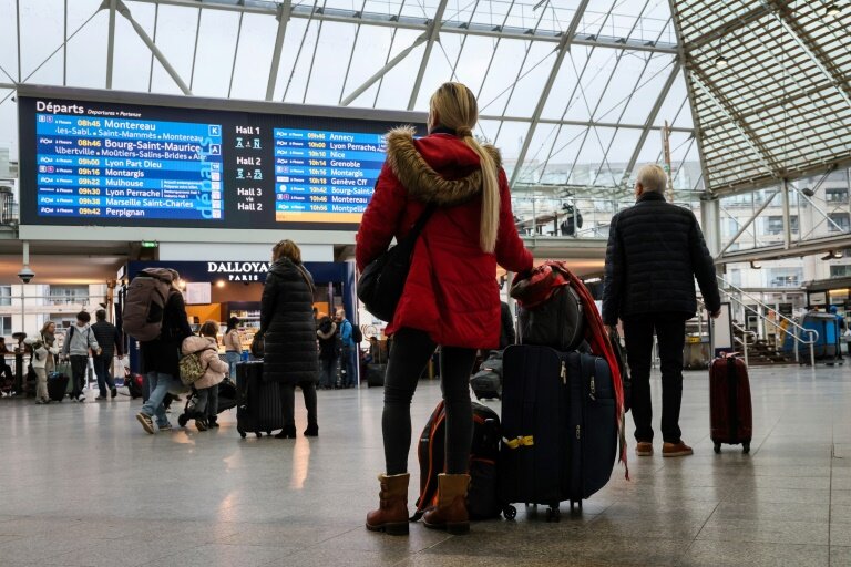 Des voyageurs devant le tableau des départs à la gare de Lyon, à Paris, le 16 février 2024 © Ian LANGSDON