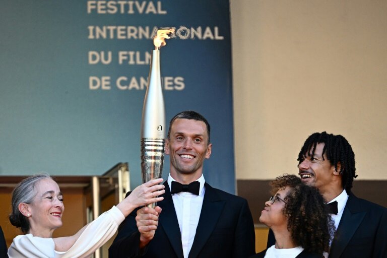 L'athlète paralympique Alexis Hanquinquant (c),  tient la flamme olympique avant la projection du film "Marcello Mio" au 77e Festival de Cannes, le 21 mai 2024 © LOIC VENANCE