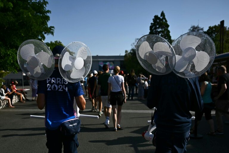 Des volontaires transportent des ventilateurs par une chaude journée d'été pendant les Jeux Olympiques de Paris 2024 devant l'Arena Paris Sud, le 29 juillet 2024 © Aris MESSINIS