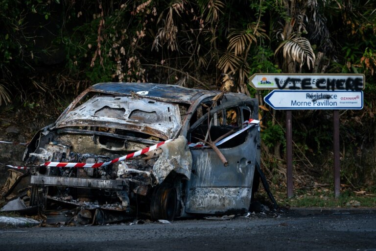 Une voiture incendiée et un graffiti "Vie chère" au Lamentin, près de Fort-de-France, le 15 octobre 2024 en Martinique © PHILIPPE LOPEZ