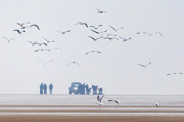 Des policiers et des CRS près d'un corps découvert tôt le matin sur la plage de Sangatte, le 22 janvier 2025 dans le Pas-de-Calais © Sameer Al-DOUMY