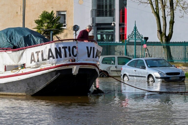 Un homme sur un bateau à côté de voitures garées dans une rue inondée à la suite d'une crue exceptionnelle de l'Ille, le 27 janvier 202 à Rennes, en Ille-et-Vilaine © Damien MEYER