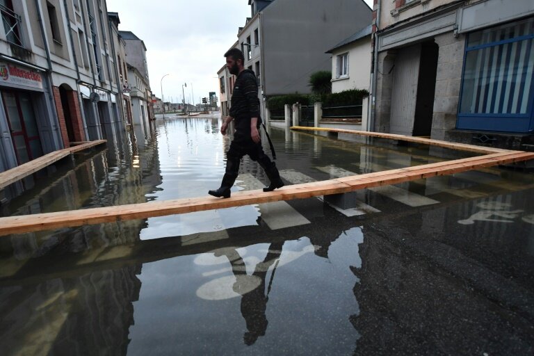 Un homme marche sur des planches surélevées pour circuler dans une rue inondée de Redon, le 30 janvier 2025, en Ille-et-Vilaine © JEAN-FRANCOIS MONIER