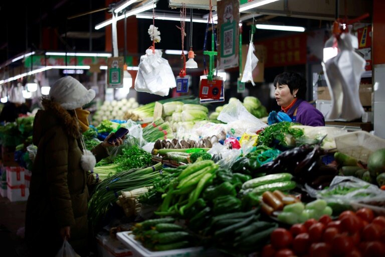 Une femme achète des légumes sur un marché à Shenyang, dans la province chinoise du Liaoning (nord-est), le 9 décembre 2024 © STR