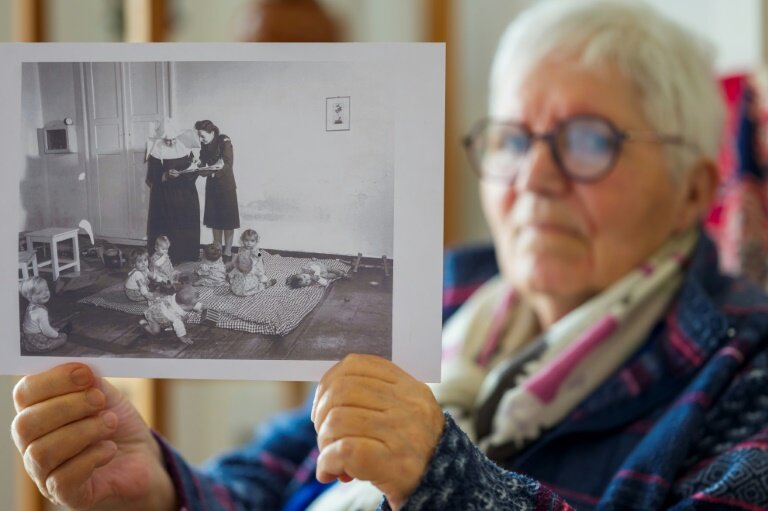 Gisèle Niango, née le 11 octobre 1943 dans une maternité "Lebensborn" en Belgique, l'une des nombreuses maternités créées par le régime nazi allemand pour "l'expansion de la race aryenne", montre une photo de son "Lebensborn", le 14 mars 2025 à Nancy, en Meurthe-et-Moselle © Jean-Christophe VERHAEGEN
