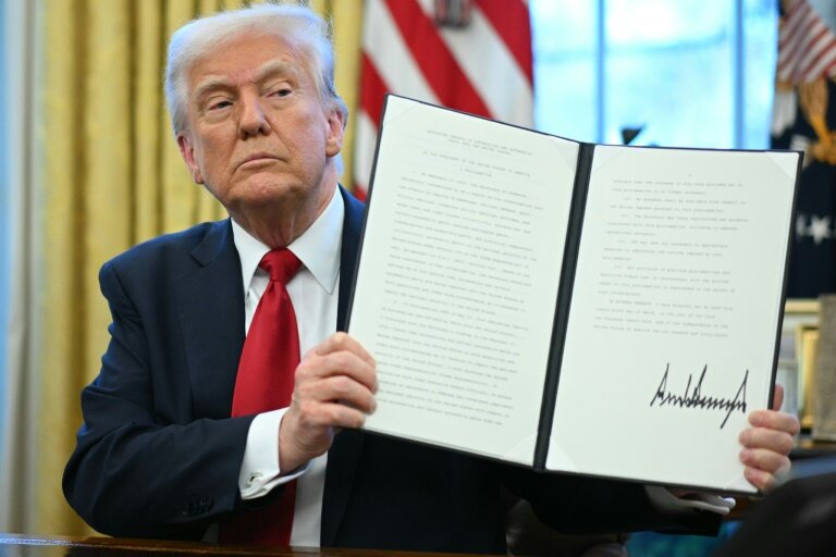 Le président américain Donald Trump montre le décret des droits de douane sur les automobiles qu'l vient de signer dans le Bureau ovale de la Maison Blanche, le 26 mars 2025 à Washington © Mandel NGAN