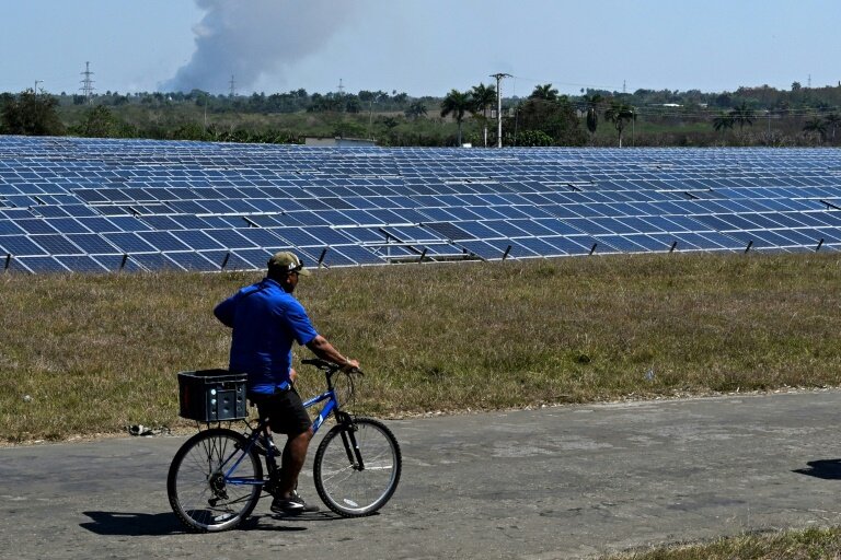 Un homme passe à vélo devant un parc photovoltaïque à Cienfuegos, le 20 mars 2025 à Cuba © Yamil LAGE