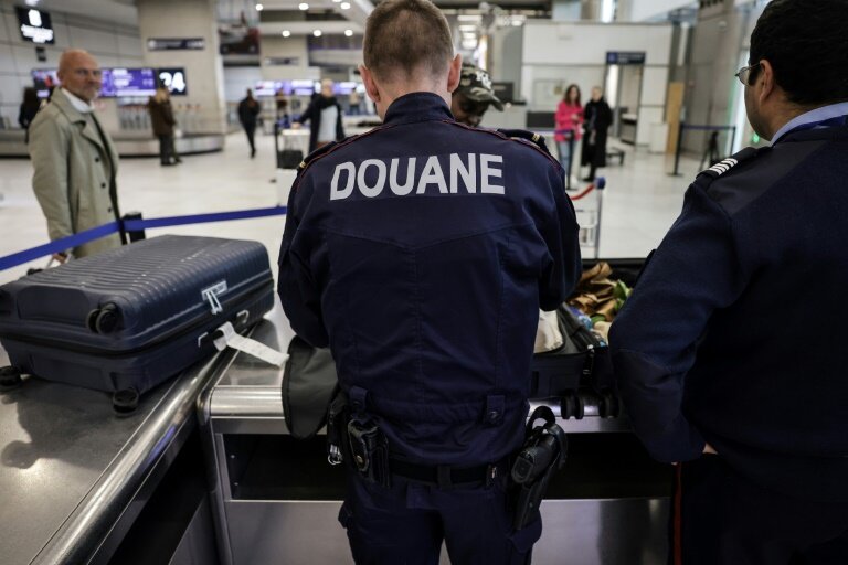 Des douaniers inspectent les bagages de passagers à l'aéroport de Roissy-Charles-de-Gaulle, au nord de Paris, le 21 mars 2025 © Thibaud MORITZ