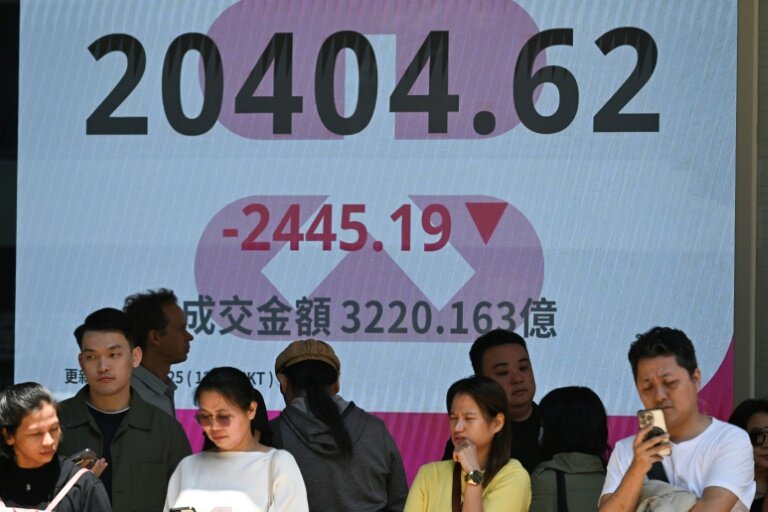 Des personnes se tiennent devant un écran de l'indice boursier Heng Seng de la Bourse de Hong Kong le 7 avril 2025 © Peter PARKS