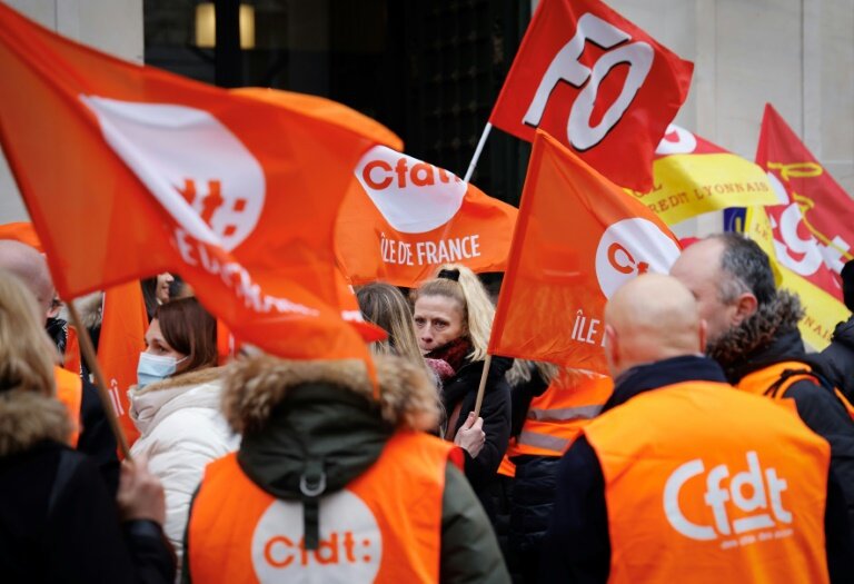 Des grévistes brandissent des drapeaux des syndicats CFDT, CGT et FO, le 17 janvier 2023 à Paris © Ludovic MARIN