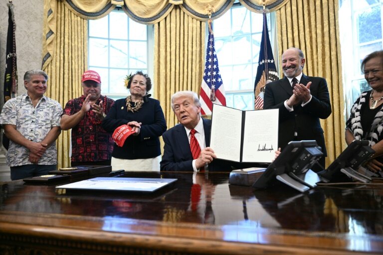 Le président américain Donald Trump montre le décret élargissant les droits de pêche dans les îles du Pacifique qu'il a signé dans le bureau ovale de la Maison-Blanche, le 17 avril 2025 à Washington © Brendan SMIALOWSKI