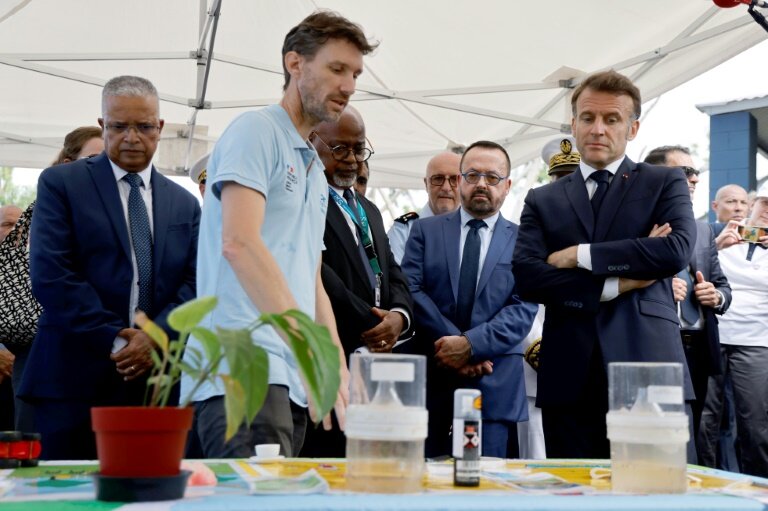 Un agent de l'ARS (g) présente des pièges à moustiques dans le cadre de la lutte contre la pandémie de chikungunya en présence du président Emmanuel Macron (d) et du ministre  en charge de la santé et de l'accès aux soins Yannick Neuder (c) à Saint-Benoit, sur l'île de La Réunion, le 22 avril 2025 © Ludovic MARIN