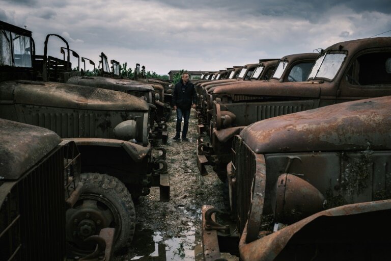 Un visiteur se promène au milieu d'épaves de véhicules de la Seconde guerre mondiale, à La Sône, le 8 mai 2025 en Isère © JEAN-PHILIPPE KSIAZEK