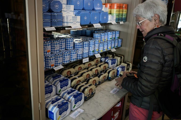 Une cliente regarde les boîtes de pastilles à la menthe Vichy produits par la confiserie Maison Moinet dans une boutique à Vichy, le 13 mai 2025 dans l'Allier © JEAN-PHILIPPE KSIAZEK
