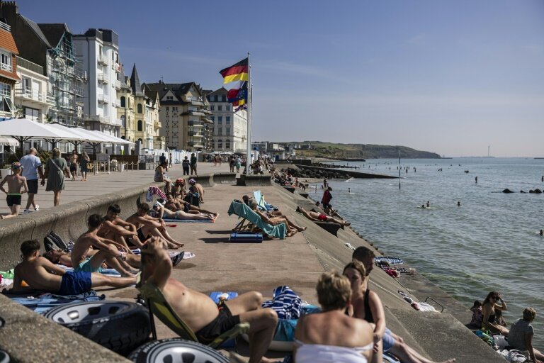 La plage de Wimereux le 18 juin 2025, avec ses baigneurs et sa gare voisine où s'abritent quelques migrants en quête d'ombre © Sameer Al-DOUMY