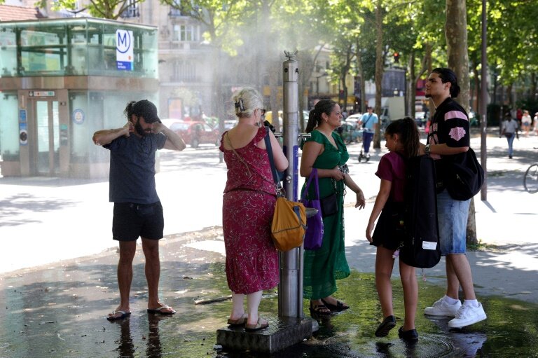 Des passants se rafraîchissent grâce à une fontaine brumisante à Paris, le 21 juin 2025 © ROMAIN PERROCHEAU