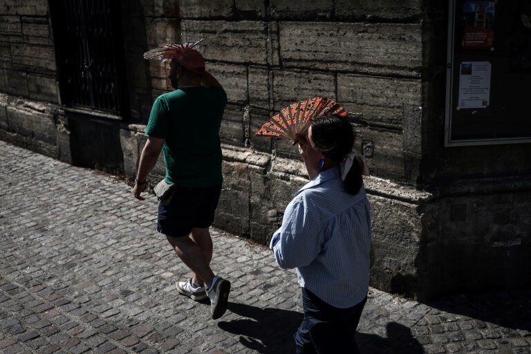 Des passants se protègent du soleil, le 1er juillet 2025 à Paris en période de canicule © Thibaud MORITZ