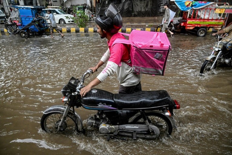 Abdullah Abbas, livreur de repas, pousse sa moto dans une rue inondée après de fortes pluies à Lahore, le 30 août 2025 au Pakistan © Aamir QURESHI