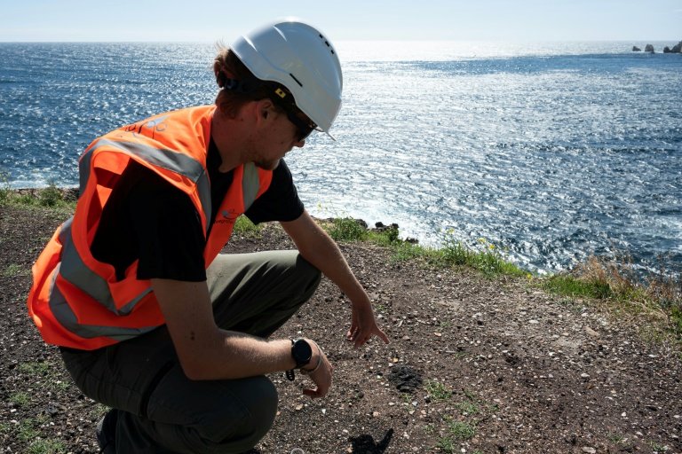 Un agent montre des dépôts de scories lors d'une visite de presse sur l'avancement des travaux de dépollution aux "Goudes", un quartier et port du 8e arrondissement de Marseille, porte sud de la ville et du Parc National des Calanques, le 11 septembre 2025 © Miguel MEDINA