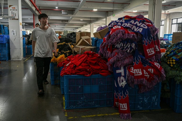 Un employé passe devant une pile de produits dans une usine qui fabrique des chapeaux et des écharpes à Yiwu, dans la province du Zhejiang, dans l'est de la Chine, le 18 septembre 2025 © Jade GAO
