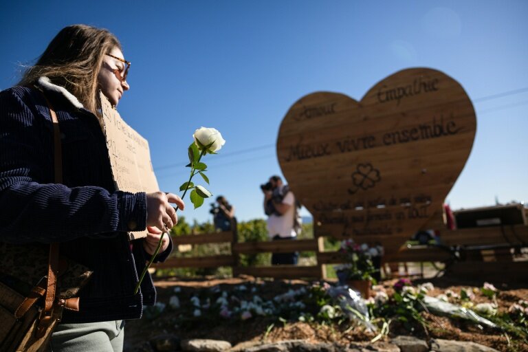 Une femme dépose une fleur devant un cœur en bois après une marche dans et autour du village de Mazan, dans le Vaucluse, pour soutenir Gisèle Pelicot et pour protester contre les violences faites aux femmes, le 5 octobre 2024 © CLEMENT MAHOUDEAU