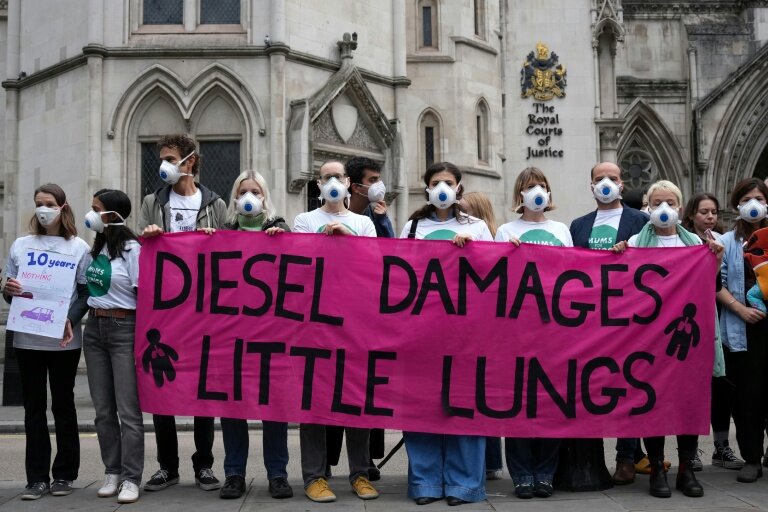 Des manifestants rassemblés devant la Haute Cour à Londres, à l'ouverture du procès de cinq géants de l'automobile impliqués dans le scandale des voitures diesel truquées, le 13 octobre 2025 © CARLOS JASSO