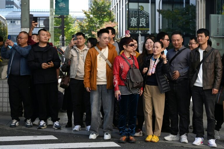 Un groupe de touristes chinois attend pour traverser une rue dans le quartier commerçant de Ginza, à Tokyo, le 16 novembre 2025 © GREG BAKER