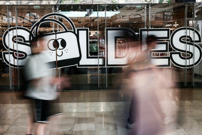 Des passants marchent à proximité de l'entrée d'un centre commercial annonçant les soldes, le 25 juin 2025 à Paris © Thibaud MORITZ