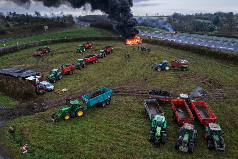 Des agriculteurs allument un feu alors qu'ils participent, avec leurs véhicules, à un blocage d'autoroute, à Poilley, dans l'ouest de la France, le 5 janvier 2026 © Damien MEYER
