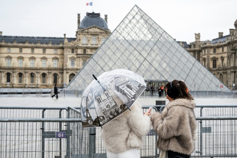 Des visiteuses devant le musée du Louvre et la pyramide conçue par l'architecte sino-américain Ieoh Ming Pei, le 12 janvier 2026 à Paris © Martin LELIEVRE