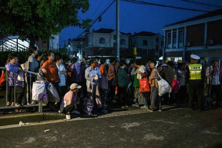 Des personnes à la recherche d'un emploi attendent à une bourse du travail informelle sur un trottoir à Shanghai, le 11 juillet 2024 © Hector RETAMAL