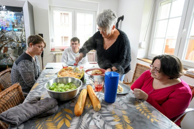 Sylvie Oswald (debout) sert le repas aux trois personnes qu'elle accueille chez elle avec sa famille, le 25 février 2025 Neufmaisons, en Meurthe-et-Moselle © Jean-Christophe VERHAEGEN