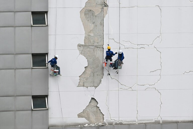 Des ouvriers réparent les dégâts sur le mur d'une tour Bangkok, le 3 avril 2025, suite au tremblement de terre du 28 mars qui a frappé le centre de la Birmanie et la Thaïlande. © MANAN VATSYAYANA