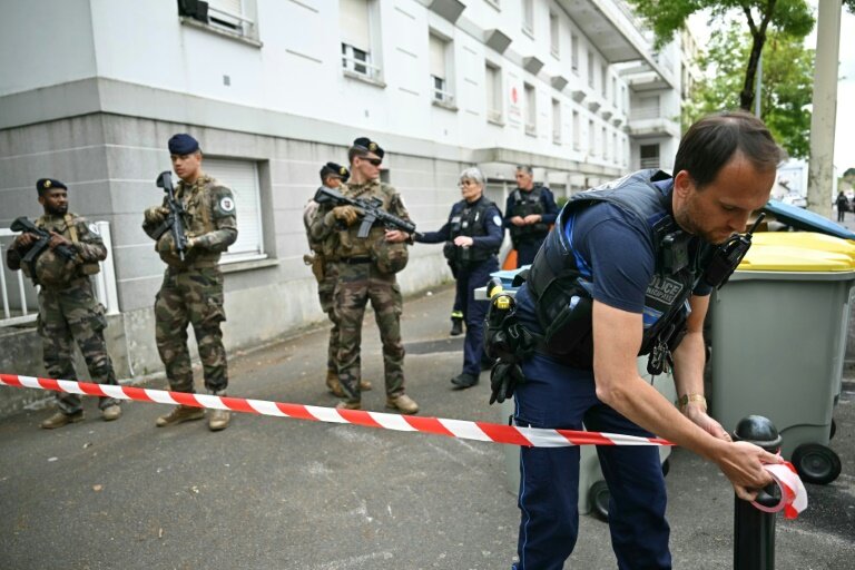 Un agent de la police municipale installe un ruban de police alors que des militaires de l'opération Sentinelle sont postés devant le lycée Notre-Dame de Toutes-Aides après une attaque au couteau, le 24 avril 2025 à Nantes, en Loire-Atlantique © Loic VENANCE
