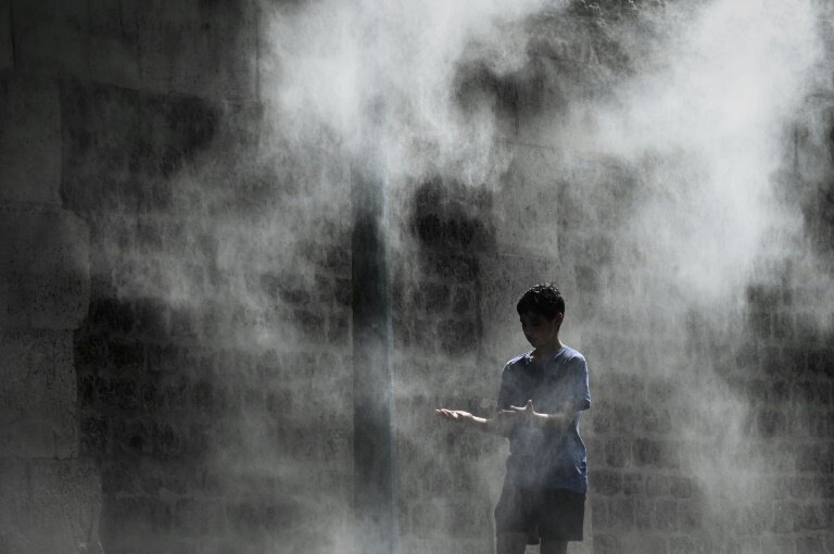 Un jeune garçon profite d'un brumisateur installé sur un quai de la Seine à Paris lors d'une canicule, le 25 juillet 2019 © PHILIPPE LOPEZ