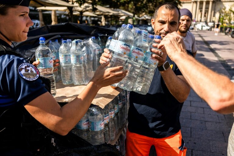 Des employés municipaux donnent des packs d'eau aux habitants lors d'une distribution d'eau potable à la suite d'une rupture de canalisation à Perpignan, le 16 juin 2025 dans les Pyrénées-Orientales © Jc Milhet