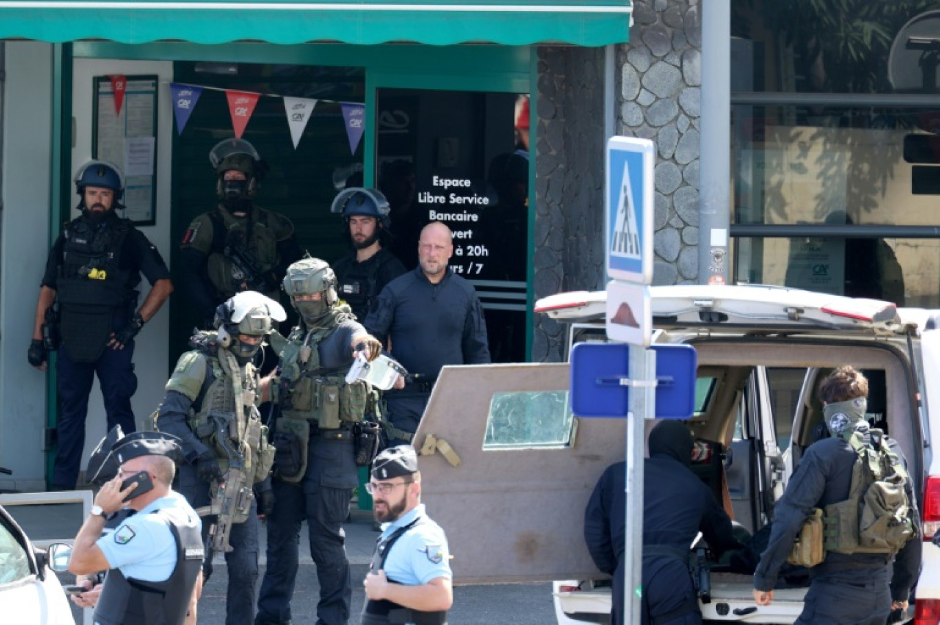 Des gendarmes et des membres de l'unité du Groupe d'intervention de la gendarmerie nationale (GIGN) devant une agence bancaire où un homme est soupçonné d'avoir mortellement frappé à l'arme blanche un agent d'entretien, le 28 octobre 2023 à La Possession, sur l'île de La Réunion © Richard BOUHET