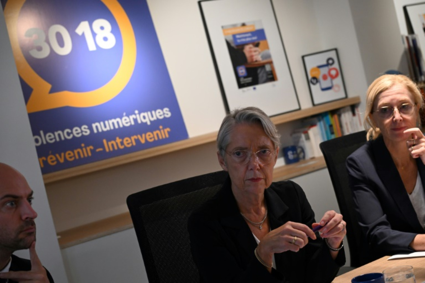 La Première ministre Elisabeth Borne (c), la Secrétaire d'Etat à l'enfance Charlotte Caubel (d) et le Secrétaire d'Etat à la transition numérique Jean-Noël Barrot dans un centre d'appel du 30 18 destiné aux victimes de cyber-harcèlement, le 10 octobre 2023 à Paris © Bertrand GUAY